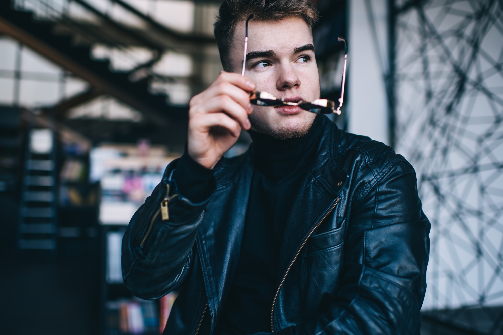 Brutal young man with sunglasses in contemporary cafe