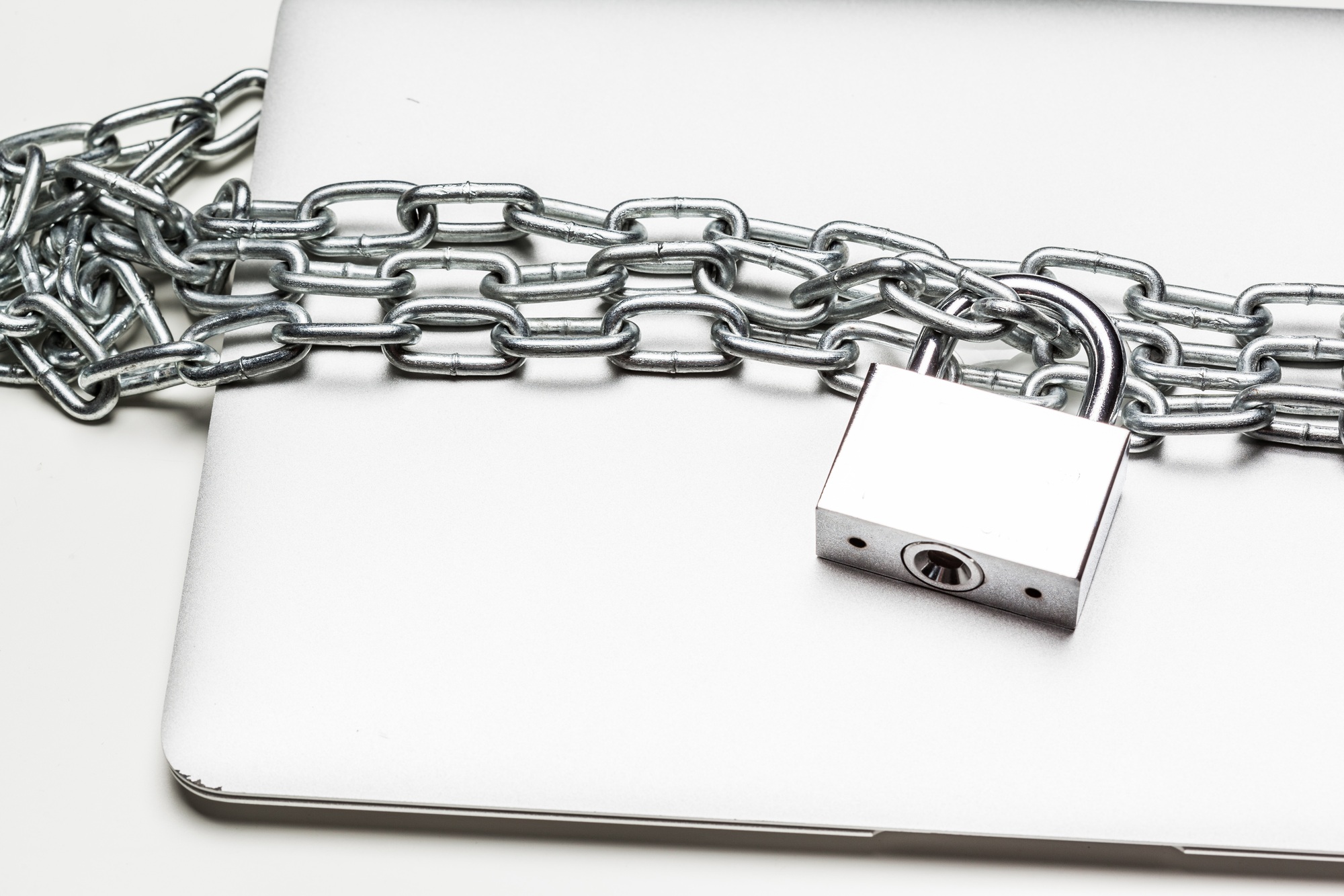 Closed laptop computer with chain wrapped around it and padlocked