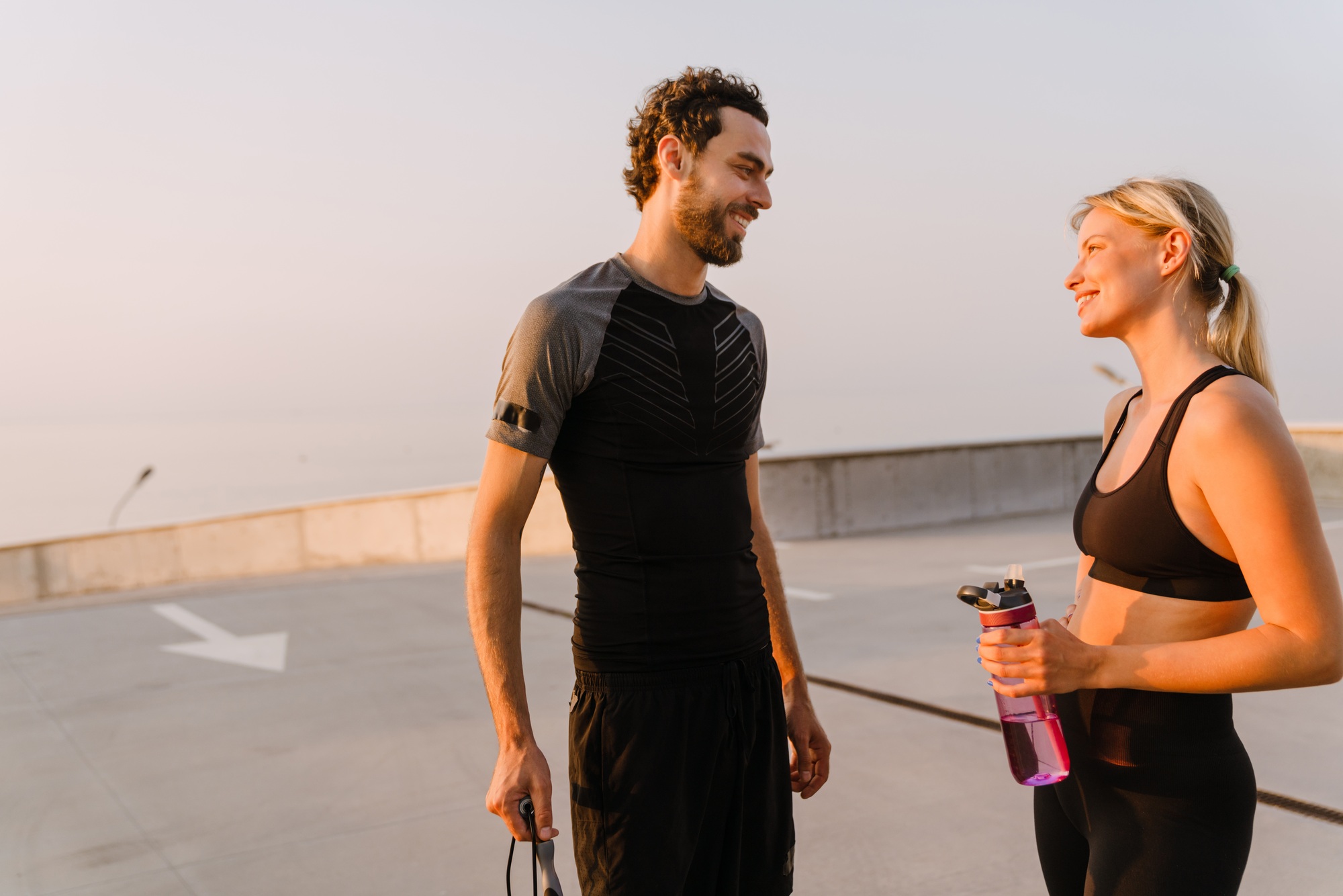 Young man and woman smiling and talking while working out together