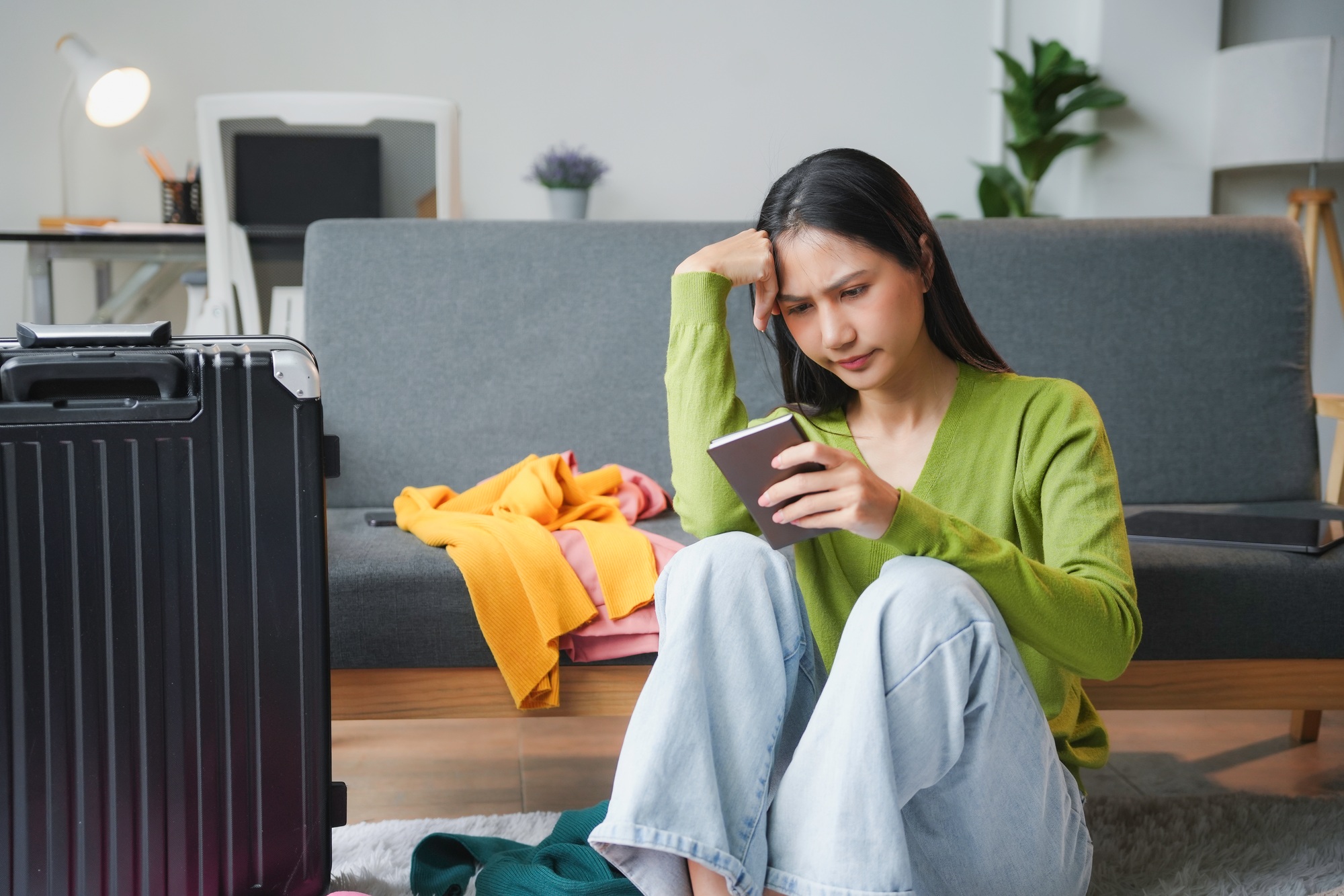 Young woman is feeling stressed while planning a trip and packing clothes